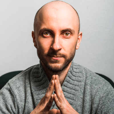 Martti posant les mains jointes devant un fond gris clair.