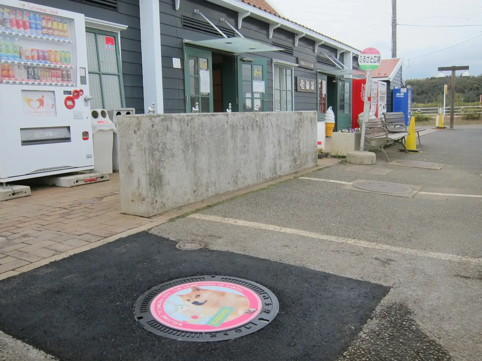 La plaque d'égoût de Kabosu placée devant le magasin de souvenirs Saranka.